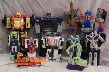 Various Transformers toys. Front row, left to right: Generation 2's Hooligan, G1's Scavenger. Middle Row, left to right: G1's Mixmaster, G1's First Aid, G1's Wheeljack, Generation 2's Jetfire, G1's Astrotrain. Back row, left to right: G1's Razorclaw, G1's Soundwave, Generation 2's Laser Optimus Prime holding Razorclaw's sword.
